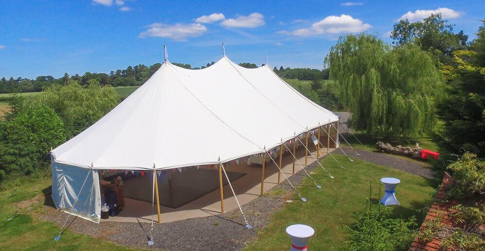Garden party with wooden poles marquee tent and canopies in the county area of Berkshire